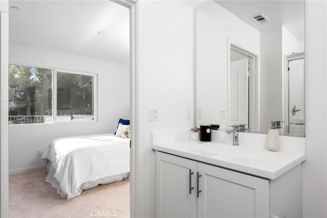 interior space with baseboards, visible vents, vanity, and ensuite bath