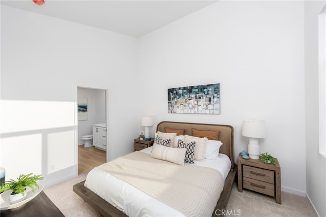 bedroom featuring light colored carpet, baseboards, and ensuite bathroom