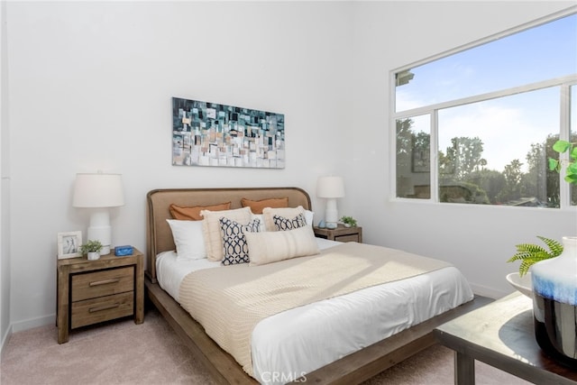 bedroom featuring light colored carpet and baseboards