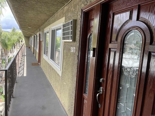 property entrance with stucco siding and a balcony