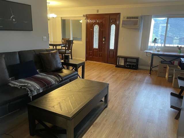 living area featuring an AC wall unit, wood finished floors, crown molding, baseboards, and a chandelier