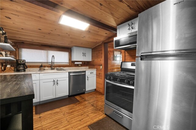 kitchen with stainless steel appliances, a sink, wood ceiling, vaulted ceiling, and hardwood / wood-style floors