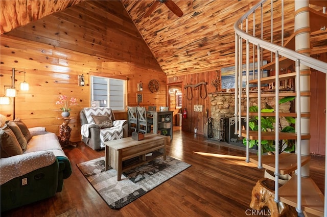 living area with wooden walls, high vaulted ceiling, stairs, and wood finished floors