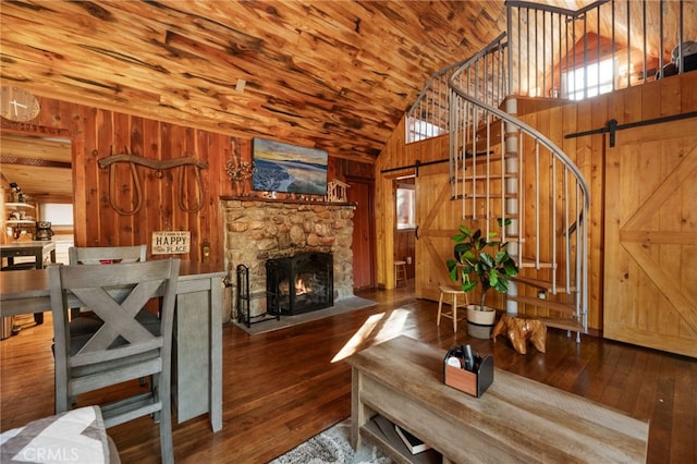 living room featuring wooden walls, stairway, a barn door, and hardwood / wood-style floors