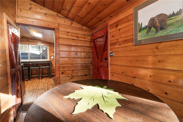 bedroom with vaulted ceiling, wooden walls, wood finished floors, and wood ceiling