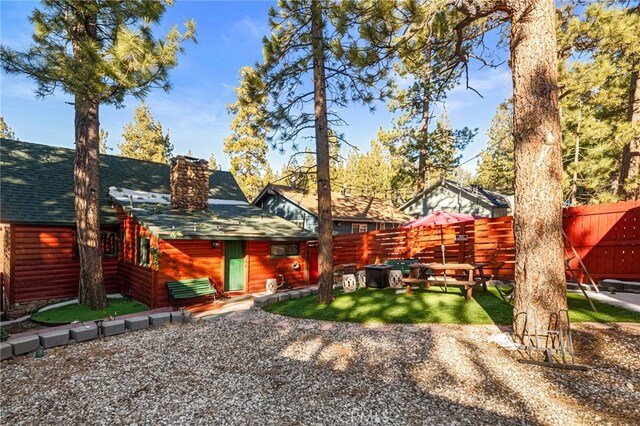 back of property with a fenced backyard, a yard, a chimney, and roof with shingles