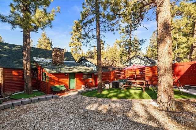 back of house featuring a fenced backyard, a lawn, and roof with shingles