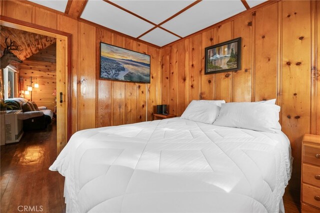 bedroom featuring dark wood-type flooring and wood walls