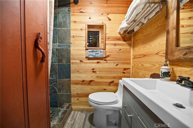 full bathroom with wood walls, a stall shower, vanity, and toilet