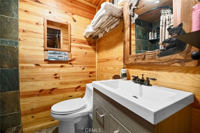 bathroom with toilet, wood walls, and vanity