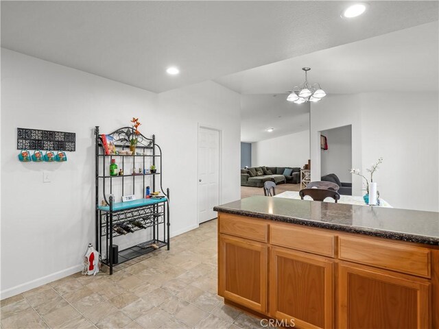 kitchen with brown cabinets, decorative light fixtures, vaulted ceiling, a chandelier, and recessed lighting