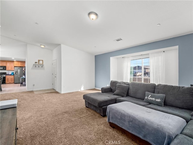 living room featuring light colored carpet, visible vents, lofted ceiling, and baseboards