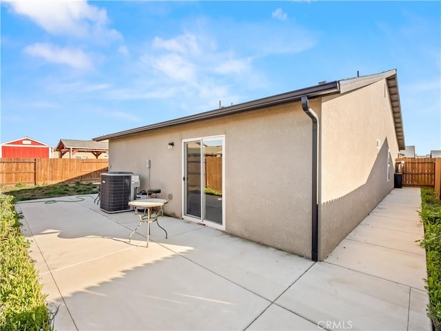 back of property with central AC, a patio area, a fenced backyard, and stucco siding