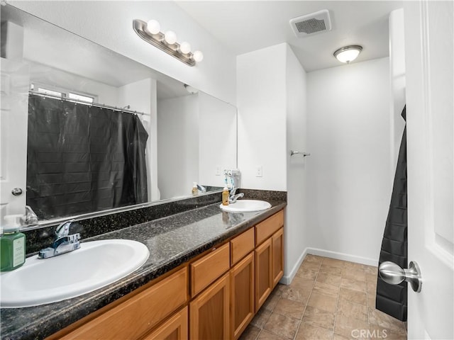 full bathroom with double vanity, baseboards, visible vents, and a sink