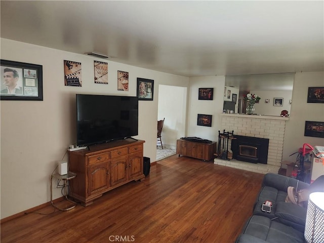 living room featuring a fireplace, wood finished floors, visible vents, and baseboards