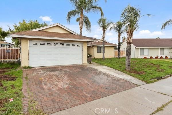 ranch-style house featuring stucco siding, a front lawn, decorative driveway, fence, and a garage