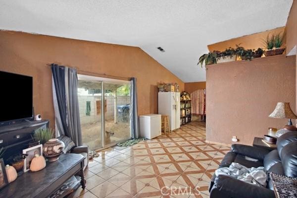 living room featuring lofted ceiling, visible vents, and a textured ceiling