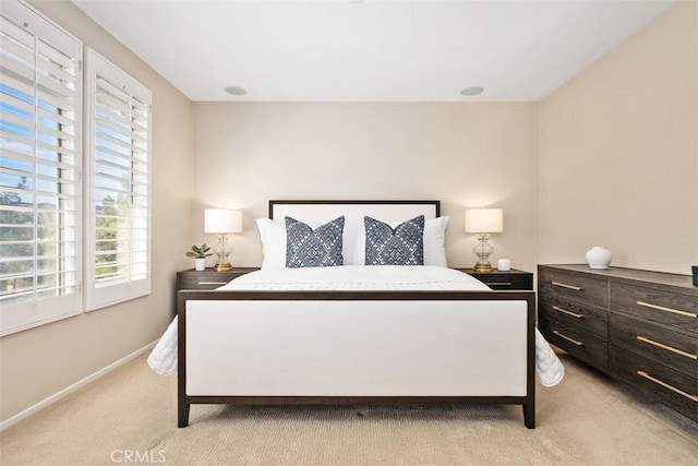 bedroom with light colored carpet and baseboards