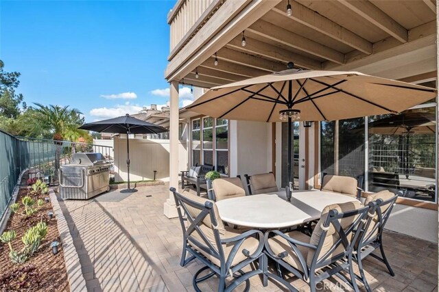 view of patio featuring outdoor dining area, fence, and grilling area