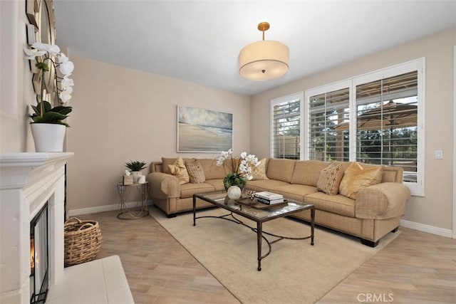 living area with light wood-style floors, a lit fireplace, and baseboards