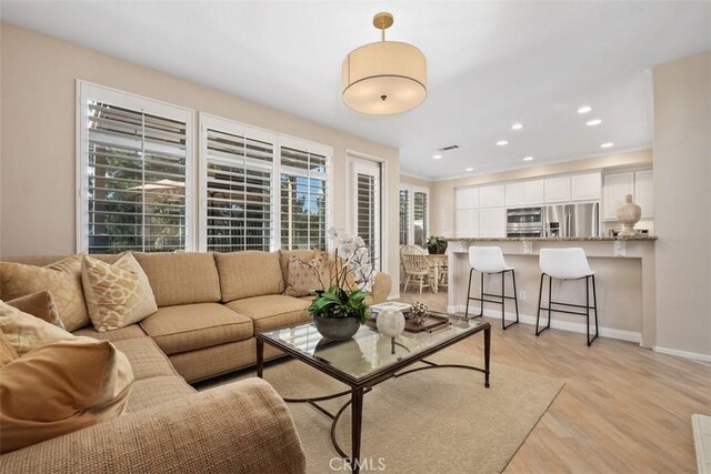 living area featuring light wood-style floors, recessed lighting, and baseboards