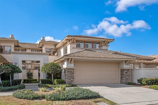 prairie-style home featuring stone siding, concrete driveway, and stucco siding