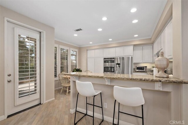 kitchen with visible vents, light wood-style flooring, white cabinetry, stainless steel fridge, and a peninsula