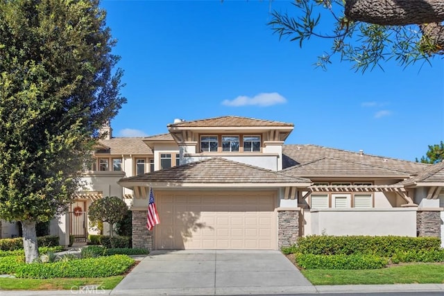 prairie-style home with a garage, stone siding, driveway, and stucco siding