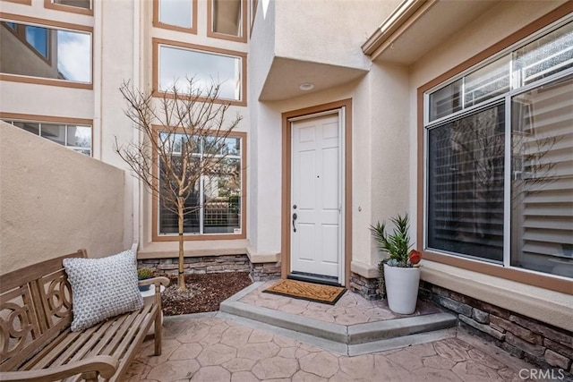 doorway to property with stone siding and stucco siding