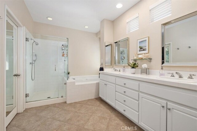 full bath with a stall shower, a garden tub, a sink, and double vanity