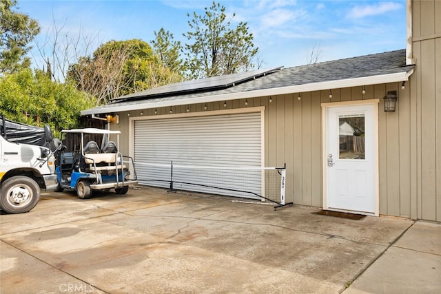 garage with roof mounted solar panels and driveway