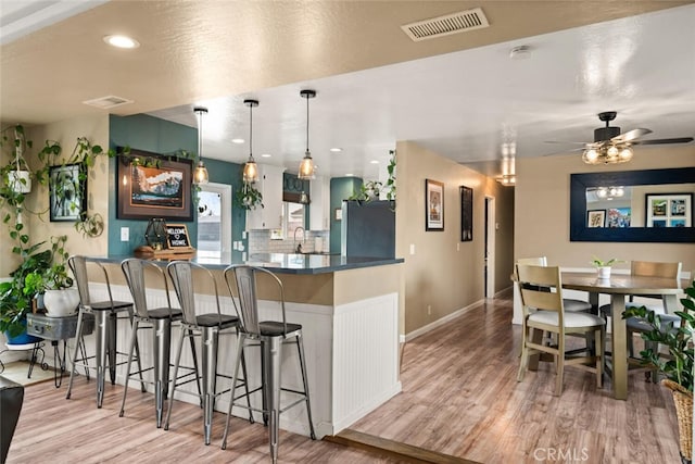 kitchen with light wood-style flooring, visible vents, and freestanding refrigerator