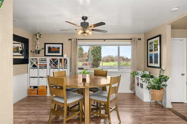 dining space featuring wainscoting, ceiling fan, and wood finished floors