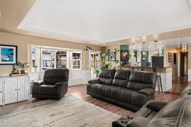 living room featuring visible vents, a raised ceiling, and wood finished floors