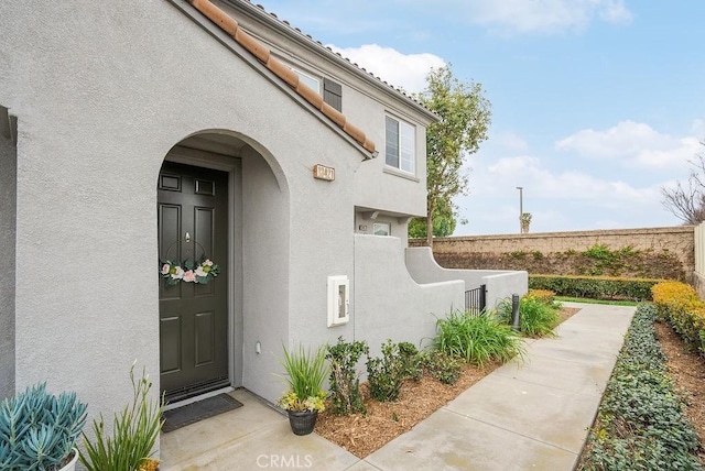 doorway to property with fence and stucco siding