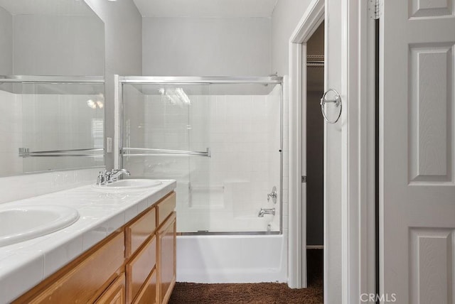 full bath with shower / bath combination with glass door, a sink, a spacious closet, and double vanity