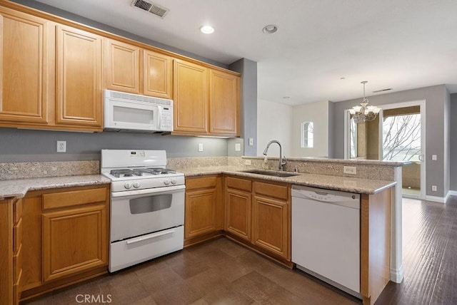 kitchen with white appliances, visible vents, a peninsula, a sink, and a notable chandelier