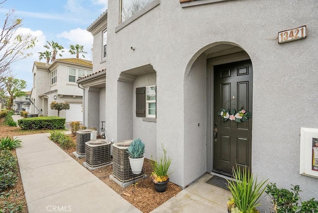 doorway to property featuring central AC unit and stucco siding