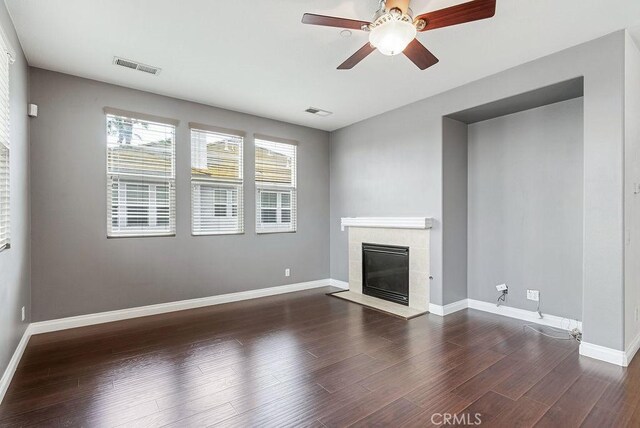 unfurnished living room featuring dark wood-style floors, baseboards, a fireplace, and visible vents