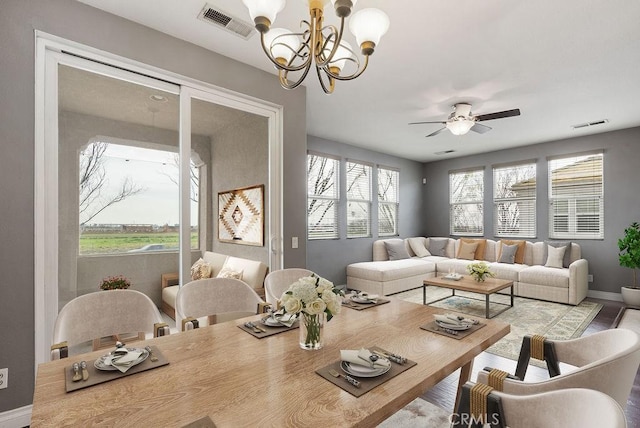 interior space featuring baseboards, visible vents, and ceiling fan with notable chandelier