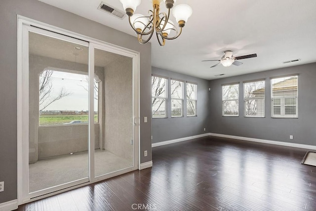 spare room with ceiling fan with notable chandelier, visible vents, baseboards, and wood finished floors