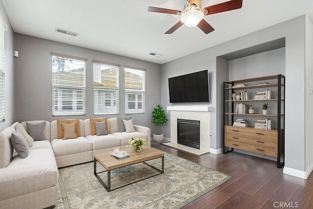 living area with dark wood-style flooring, a fireplace, visible vents, and baseboards