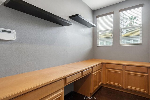 unfurnished office featuring dark wood-style flooring and built in desk