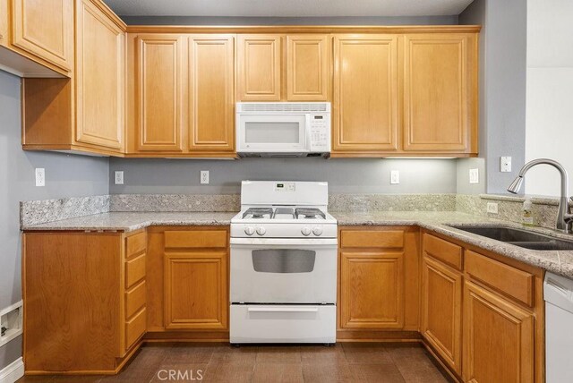 kitchen featuring white appliances, a sink, and light stone counters