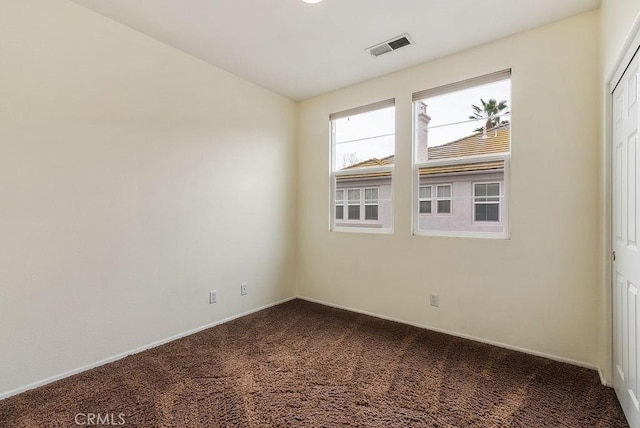 empty room featuring vaulted ceiling, visible vents, and dark carpet