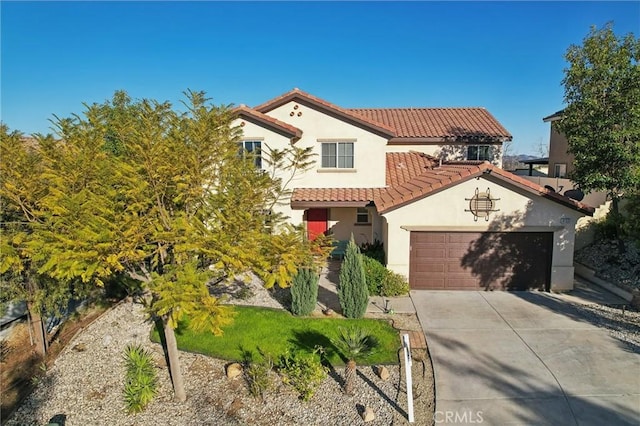 mediterranean / spanish-style home with stucco siding, a garage, driveway, and a tile roof