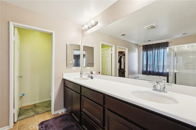 full bath featuring a walk in closet, double vanity, a stall shower, and a sink