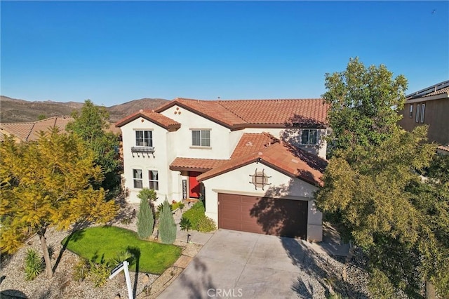 mediterranean / spanish-style home featuring stucco siding, concrete driveway, a garage, a tile roof, and a mountain view