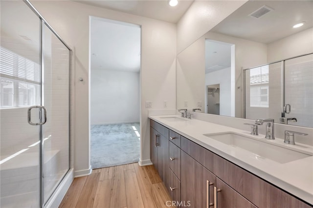 full bathroom featuring visible vents, hardwood / wood-style flooring, a stall shower, and a sink