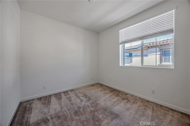 carpeted spare room featuring baseboards